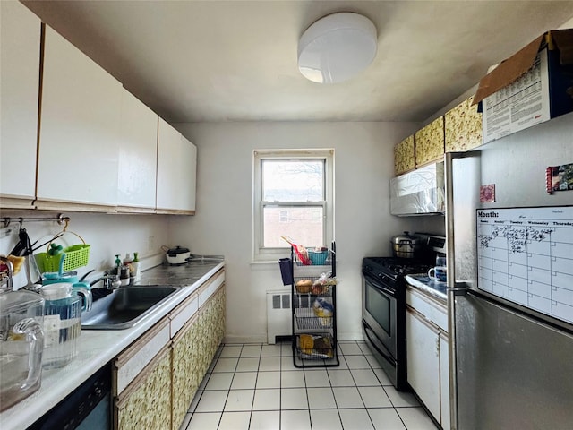 kitchen with radiator, white cabinetry, sink, light tile patterned flooring, and appliances with stainless steel finishes