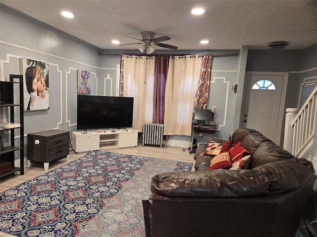 living room featuring ceiling fan, light hardwood / wood-style floors, and radiator