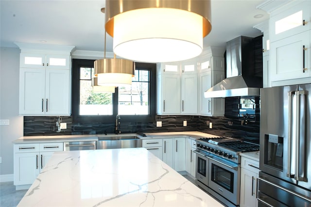 kitchen with backsplash, wall chimney exhaust hood, white cabinetry, and stainless steel appliances