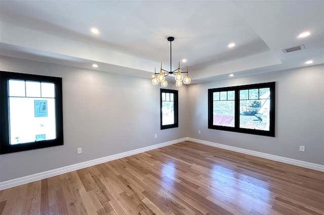 spare room featuring a chandelier, a tray ceiling, and hardwood / wood-style flooring