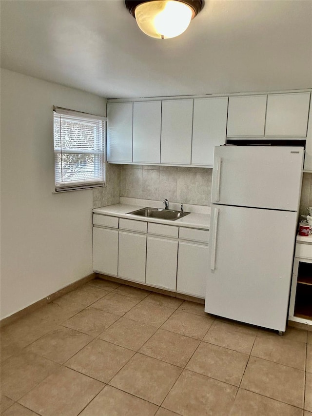 kitchen with tasteful backsplash, sink, white refrigerator, white cabinetry, and light tile patterned flooring