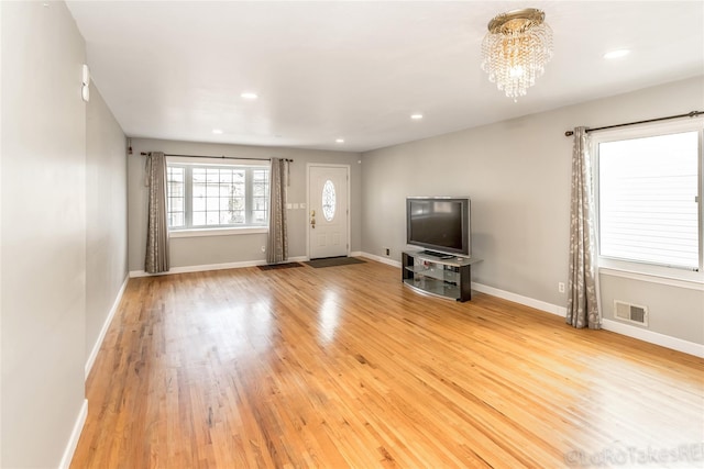 unfurnished living room with a chandelier and light hardwood / wood-style floors