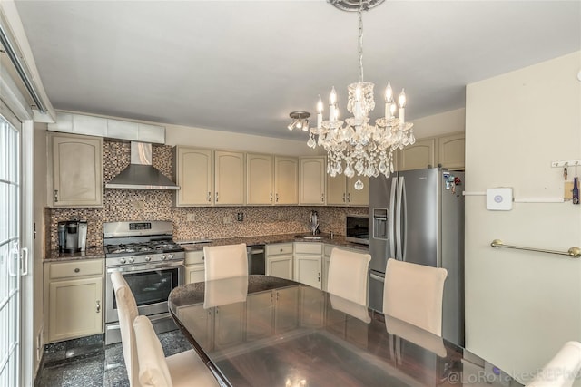 kitchen featuring wall chimney exhaust hood, hanging light fixtures, stainless steel appliances, tasteful backsplash, and a chandelier