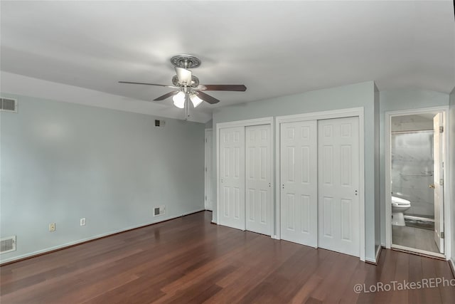 unfurnished bedroom featuring dark hardwood / wood-style flooring, connected bathroom, ceiling fan, and multiple closets