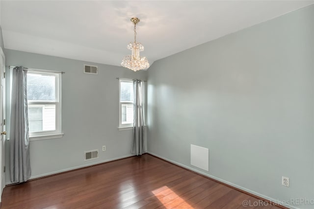 unfurnished room with dark hardwood / wood-style flooring, plenty of natural light, and an inviting chandelier