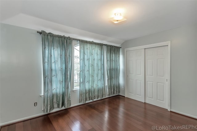 unfurnished bedroom featuring dark hardwood / wood-style flooring, a closet, and lofted ceiling