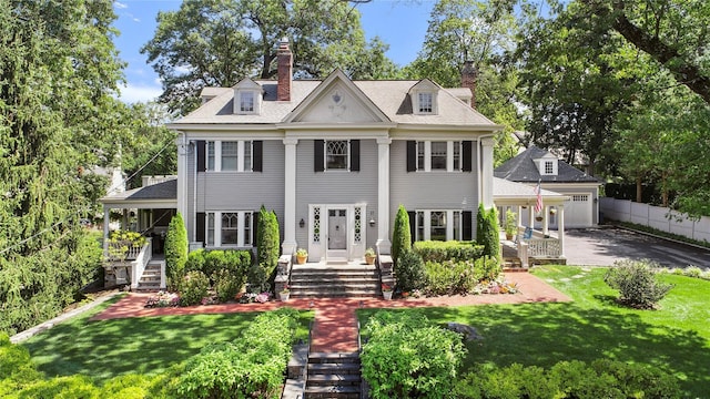 colonial home with covered porch and a front lawn