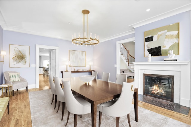 dining space with light hardwood / wood-style floors, ornamental molding, and an inviting chandelier