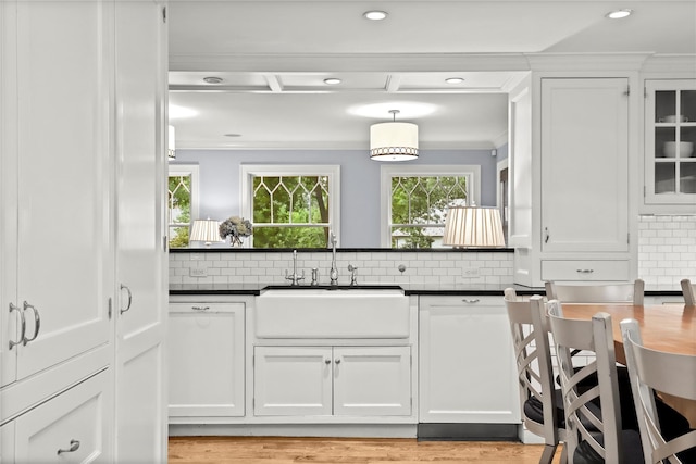 kitchen with backsplash, sink, hanging light fixtures, ornamental molding, and white cabinetry