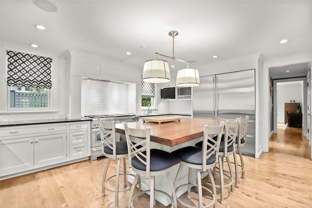 kitchen featuring backsplash, high quality appliances, white cabinets, a kitchen island, and hanging light fixtures