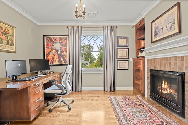 office featuring a chandelier, ornamental molding, light wood-type flooring, and a brick fireplace