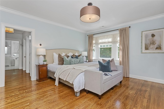 bedroom with hardwood / wood-style floors, crown molding, and connected bathroom