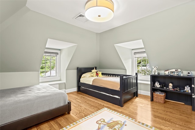 bedroom with hardwood / wood-style flooring, vaulted ceiling, and multiple windows