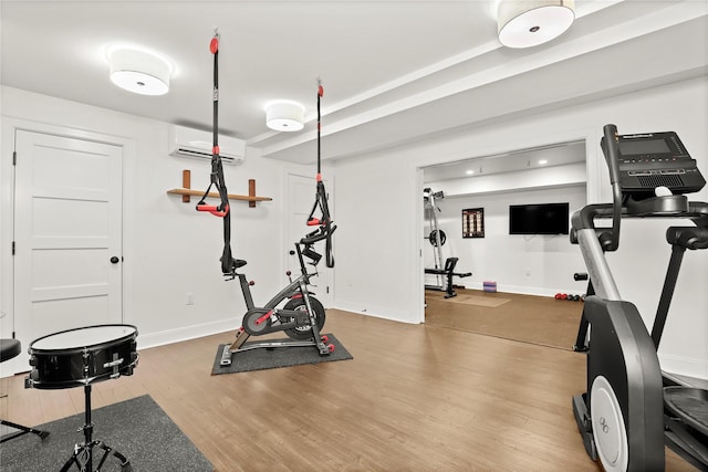 exercise area featuring hardwood / wood-style floors and a wall unit AC