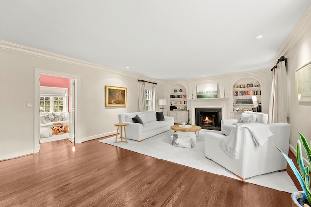 living room with hardwood / wood-style floors, built in features, and crown molding