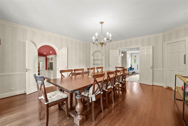 dining space featuring built in shelves, crown molding, dark hardwood / wood-style flooring, and a chandelier