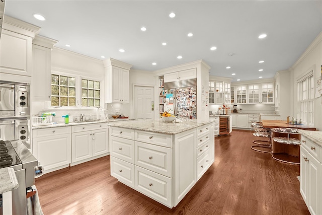 kitchen with built in appliances, a kitchen island, white cabinets, and stacked washer and clothes dryer