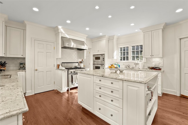 kitchen featuring white cabinets, light stone countertops, high end stove, and wall chimney range hood