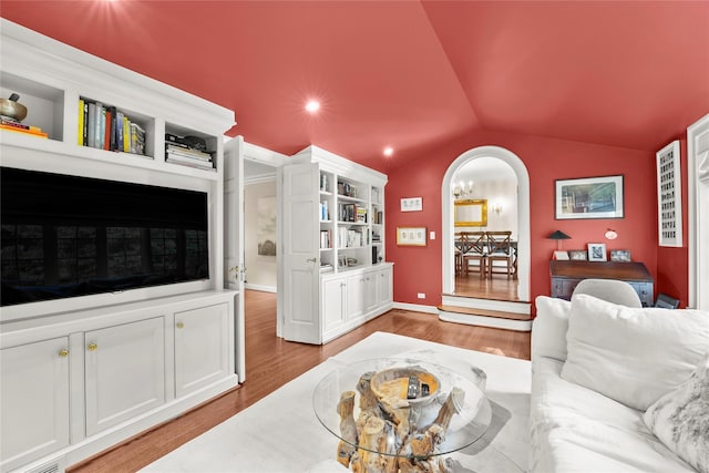 living room with built in features, light hardwood / wood-style floors, and vaulted ceiling