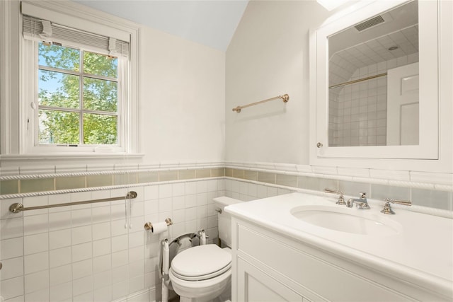 bathroom with tile walls, vanity, lofted ceiling, and toilet