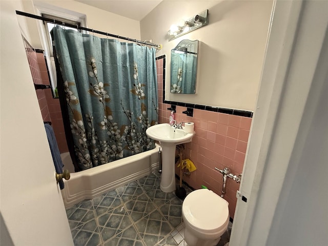 bathroom with tile patterned floors, shower / tub combo with curtain, tile walls, and toilet