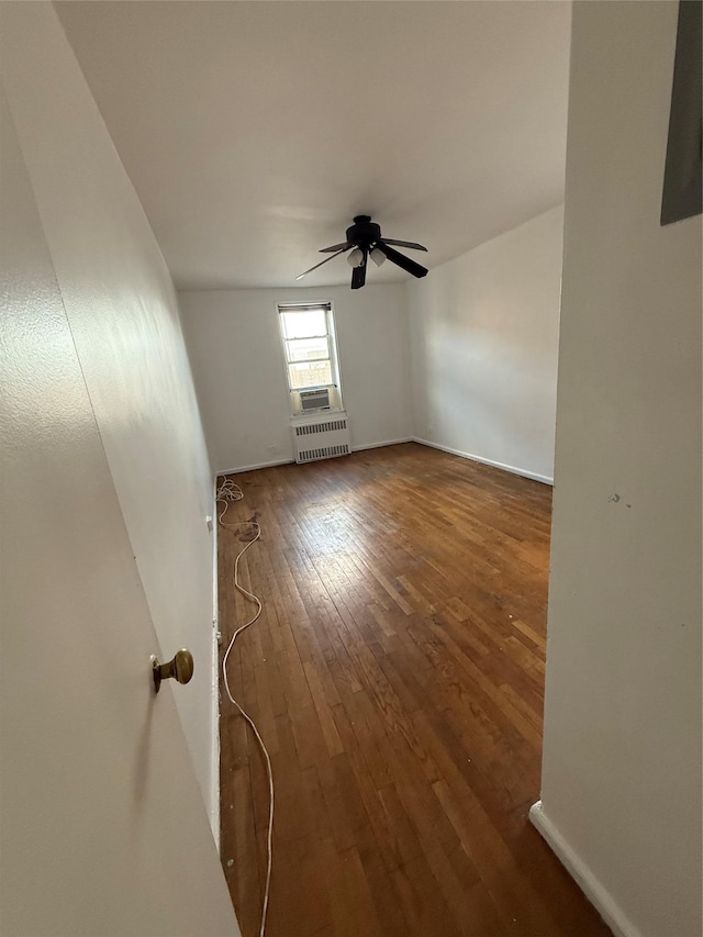 unfurnished room featuring ceiling fan, dark hardwood / wood-style flooring, and radiator heating unit