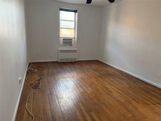 empty room featuring cooling unit, radiator, dark wood-type flooring, and ceiling fan