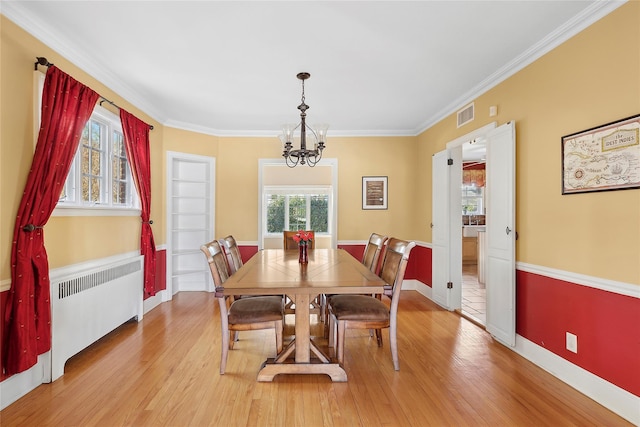 dining space featuring a chandelier, crown molding, radiator heating unit, and light hardwood / wood-style floors