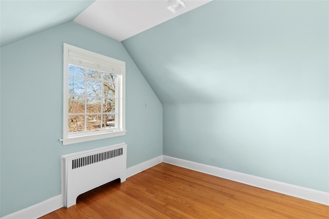 bonus room with hardwood / wood-style flooring, radiator, and vaulted ceiling