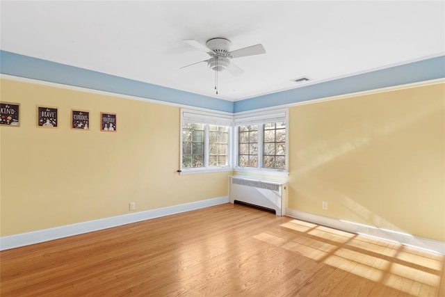 unfurnished room featuring radiator heating unit, light wood-type flooring, and ceiling fan