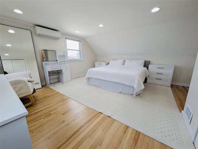 bedroom featuring an AC wall unit, vaulted ceiling, and light wood-type flooring