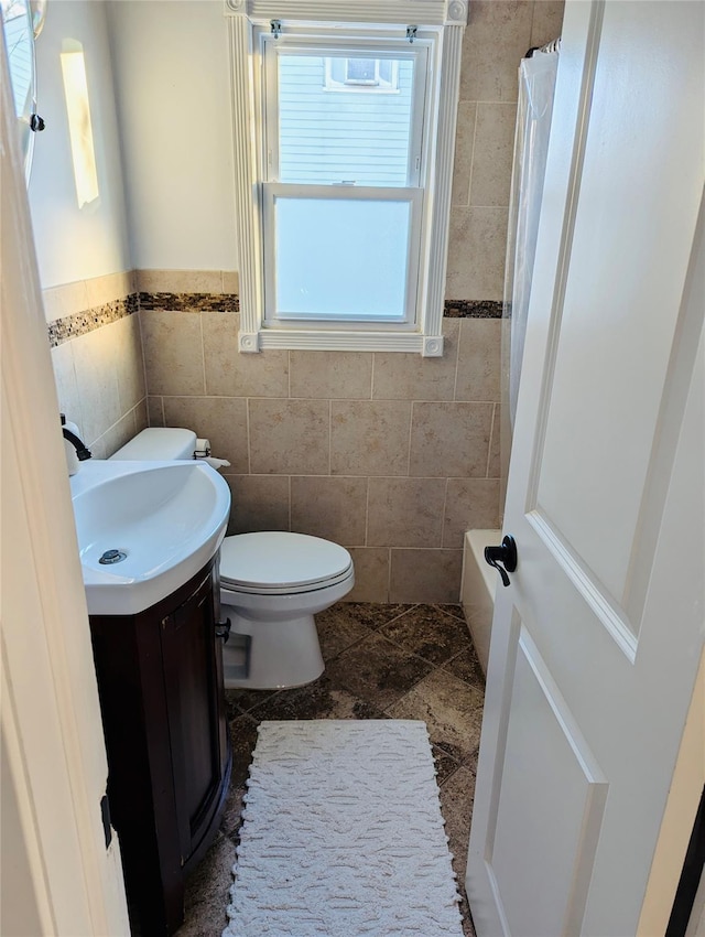 bathroom with a shower with shower curtain, vanity, toilet, and tile walls