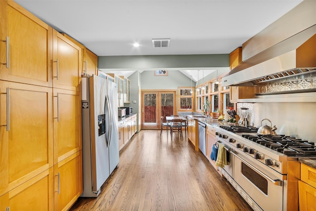 kitchen featuring lofted ceiling, sink, stainless steel appliances, dark hardwood / wood-style flooring, and exhaust hood