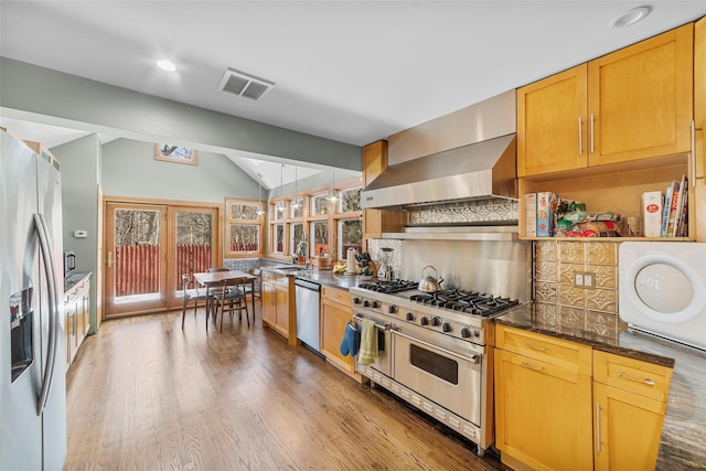 kitchen featuring lofted ceiling, sink, extractor fan, stainless steel appliances, and light hardwood / wood-style floors