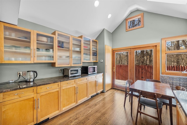 kitchen featuring high vaulted ceiling, dark stone countertops, and light hardwood / wood-style floors