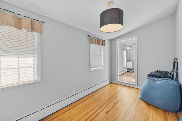 interior space featuring a baseboard radiator, lofted ceiling, and hardwood / wood-style floors