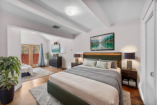 bedroom with lofted ceiling with beams, wood-type flooring, and crown molding