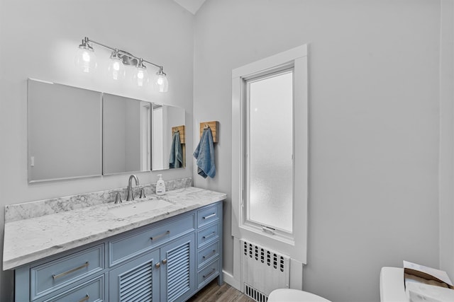 bathroom featuring vanity, wood-type flooring, radiator, and toilet