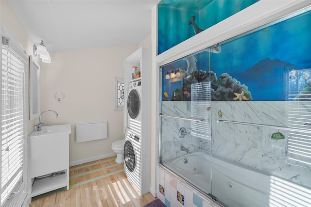 laundry area featuring stacked washer and clothes dryer and light hardwood / wood-style flooring