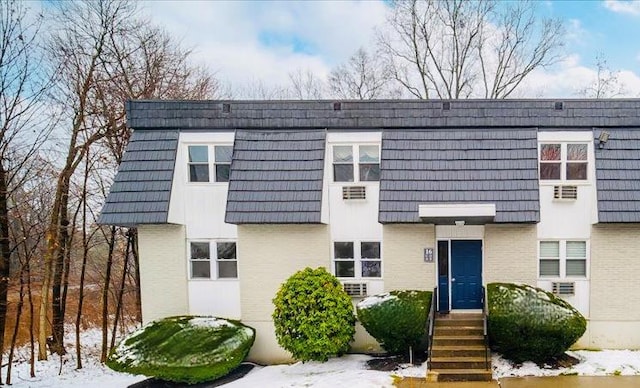 townhome / multi-family property featuring mansard roof and brick siding