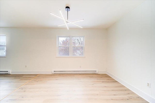 unfurnished room with hardwood / wood-style flooring, an inviting chandelier, and a baseboard heating unit