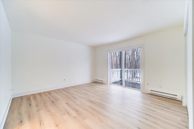 unfurnished room featuring baseboard heating and light hardwood / wood-style flooring