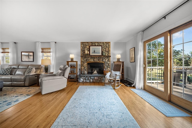 living room featuring a fireplace, light hardwood / wood-style flooring, and a baseboard heating unit