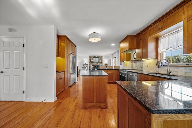 kitchen featuring a kitchen island, sink, kitchen peninsula, stainless steel appliances, and light wood-type flooring