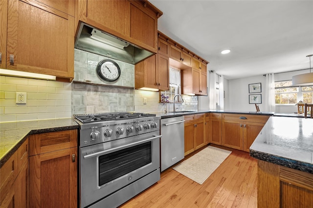 kitchen with light hardwood / wood-style flooring, stainless steel appliances, extractor fan, decorative backsplash, and kitchen peninsula