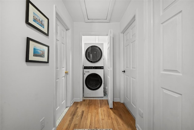 washroom with stacked washer and clothes dryer and light wood-type flooring