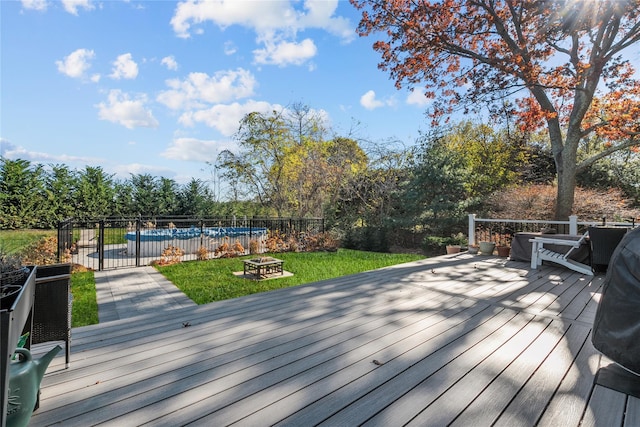 wooden deck with a pool, a fire pit, and a lawn