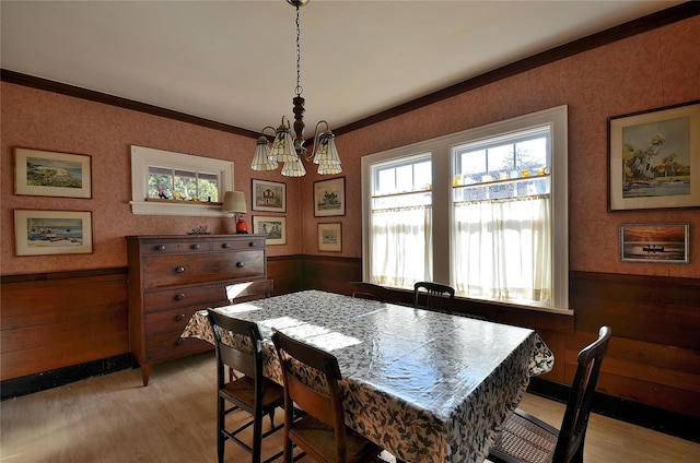 dining area featuring light hardwood / wood-style floors, ornamental molding, and a notable chandelier