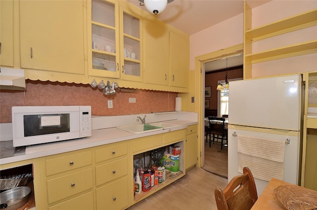 kitchen featuring pendant lighting, light wood-type flooring, sink, and tasteful backsplash