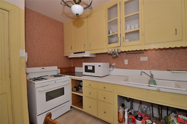 kitchen featuring sink, white appliances, and light wood-type flooring